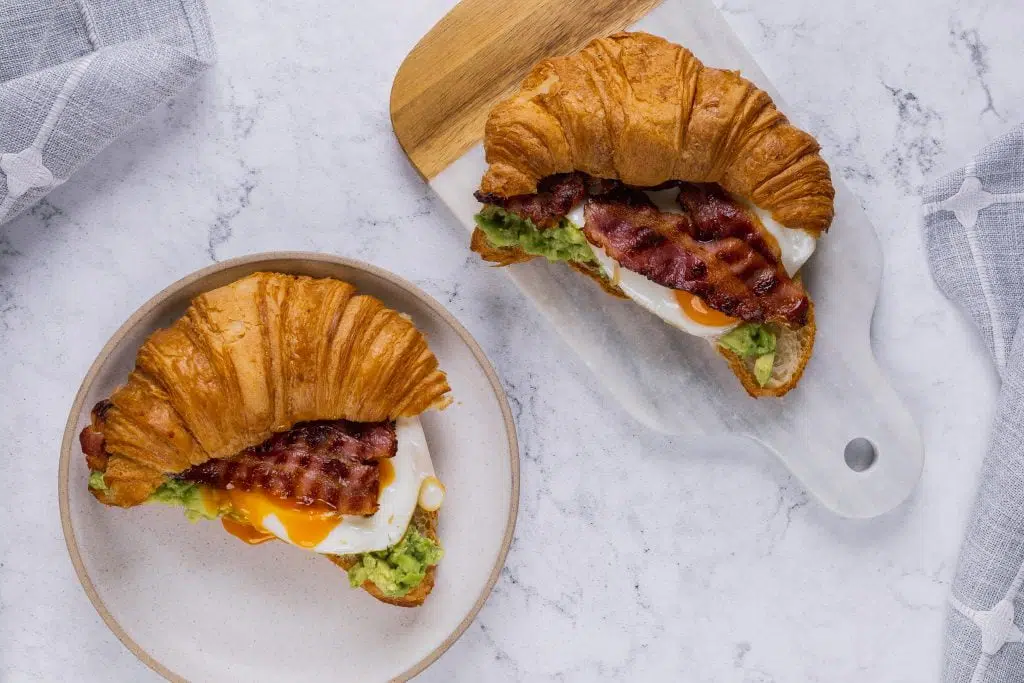 The ultimate brunch with loaded croissants. Croissant with avocado smash with a pinch of chilli flakes, rich fried egg with crispy bacon.